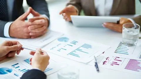 Image of business documents, pen and glasses on workplace during meeting of partners