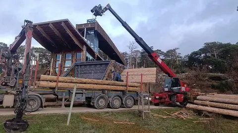 Los trabajos de colocación de nuevos troncos en la Casa de la Madera se ejecutan con la maquinaria precisa