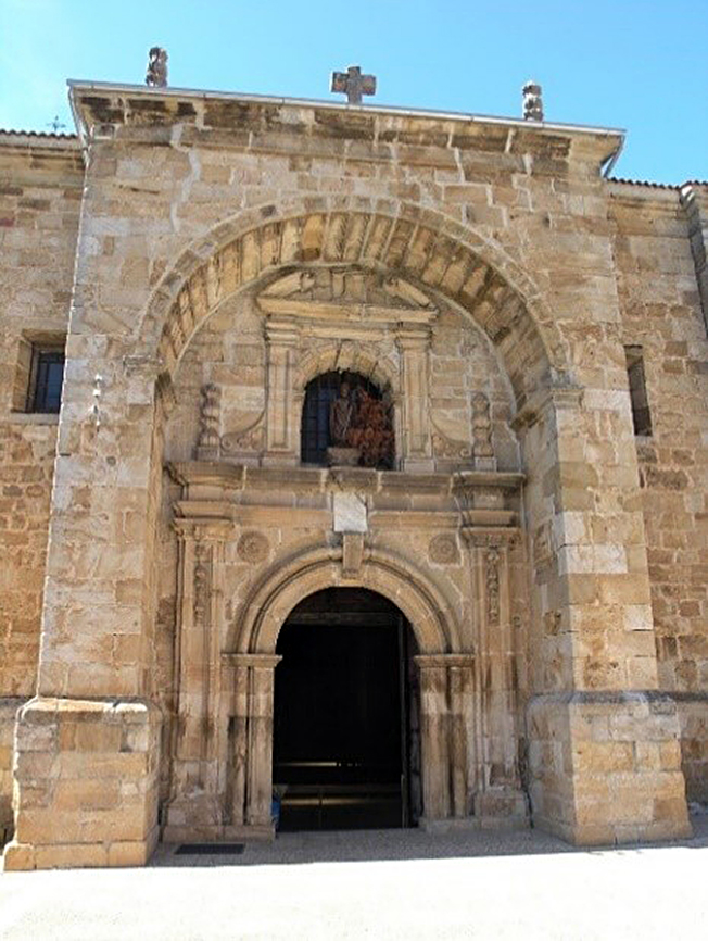 Entrada de la iglesia de Huerta de Arriba con la lápi-da de los caídos por encima del arco de la puerta.